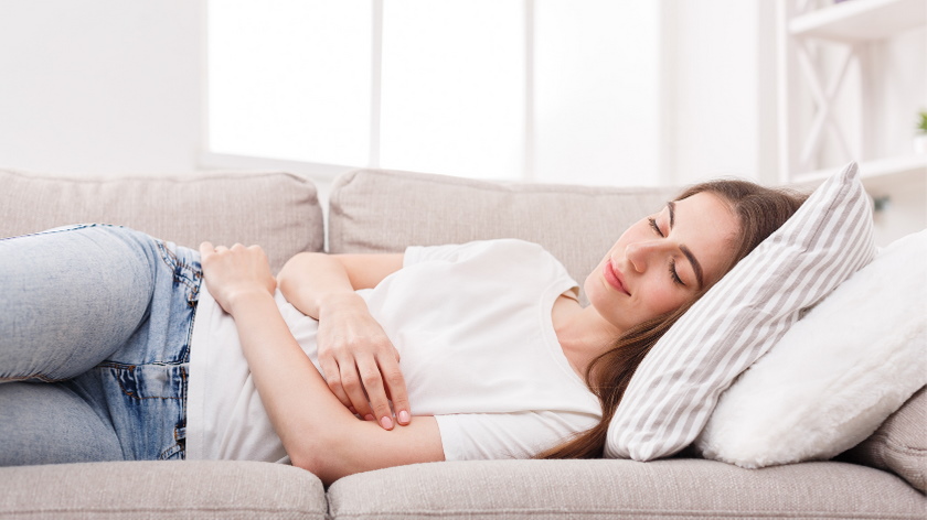 A woman is lying on a couch, taking a nap