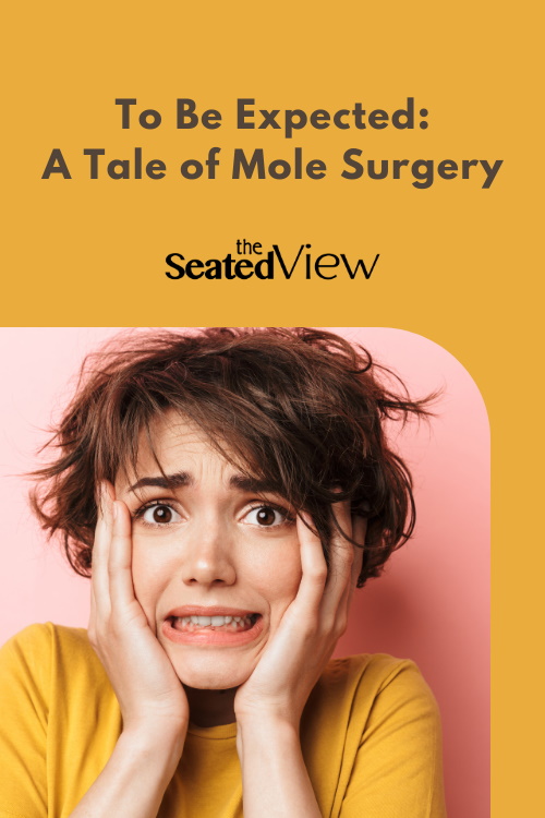 To Be Expected: A Tale of Mole Surgery. My experience with mole removal after a diagnosis of melanoma. A white woman with short dark hair is clasping her face looking scared.