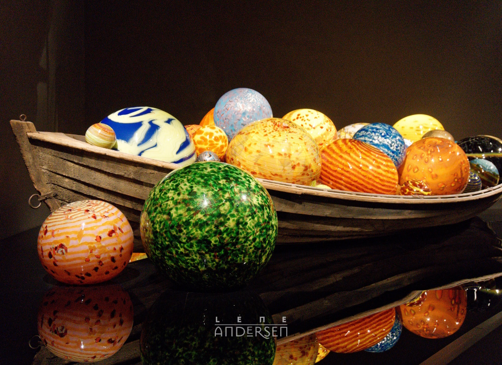 A collection of colourful glass globes in an old rowboat. Glass culture by Chihuly