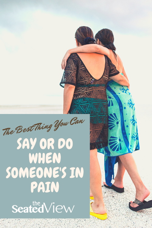 Two women walk along a beach, see from the back. They have their arms around each other. There is a field with the post title "The Best Thing You Can Say or Do When Someone's in Pain and the logo of The Seated View blog.