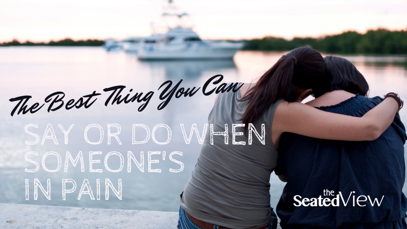 Two women sit on a bench in front of a stretch of water with a boat in it. We see them from the back. One has her arm around the other. The post title says "The Best Thing You Can Say or Do When Someone's in Pain and the logo of The Seated View blog.